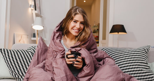 smiling woman wrapped in a blanket on the couch on a chilly day